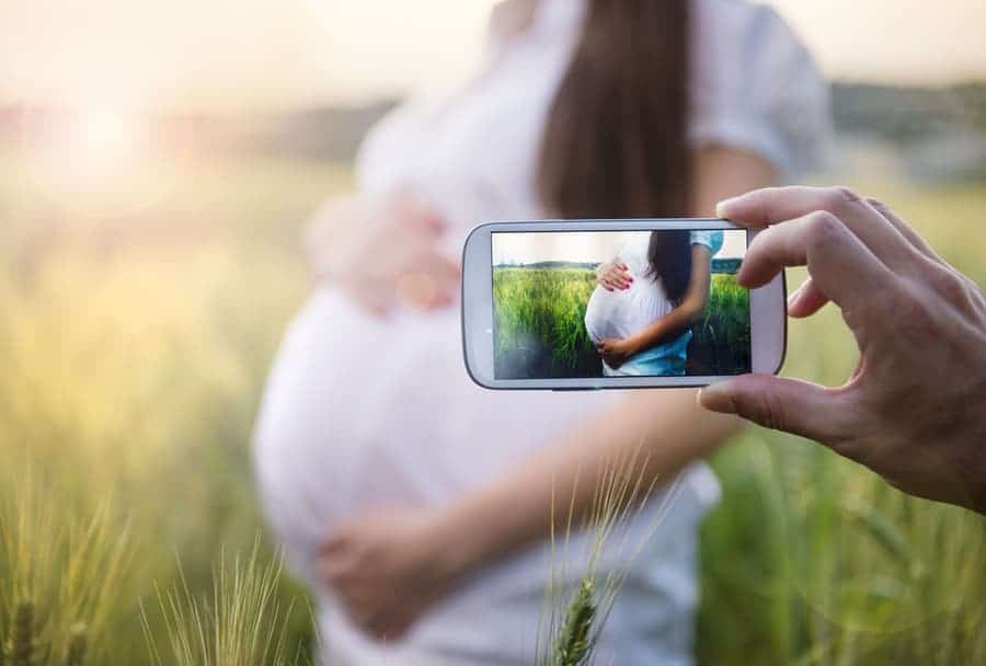 person taking a picture with a smartphone of a pregnant woman